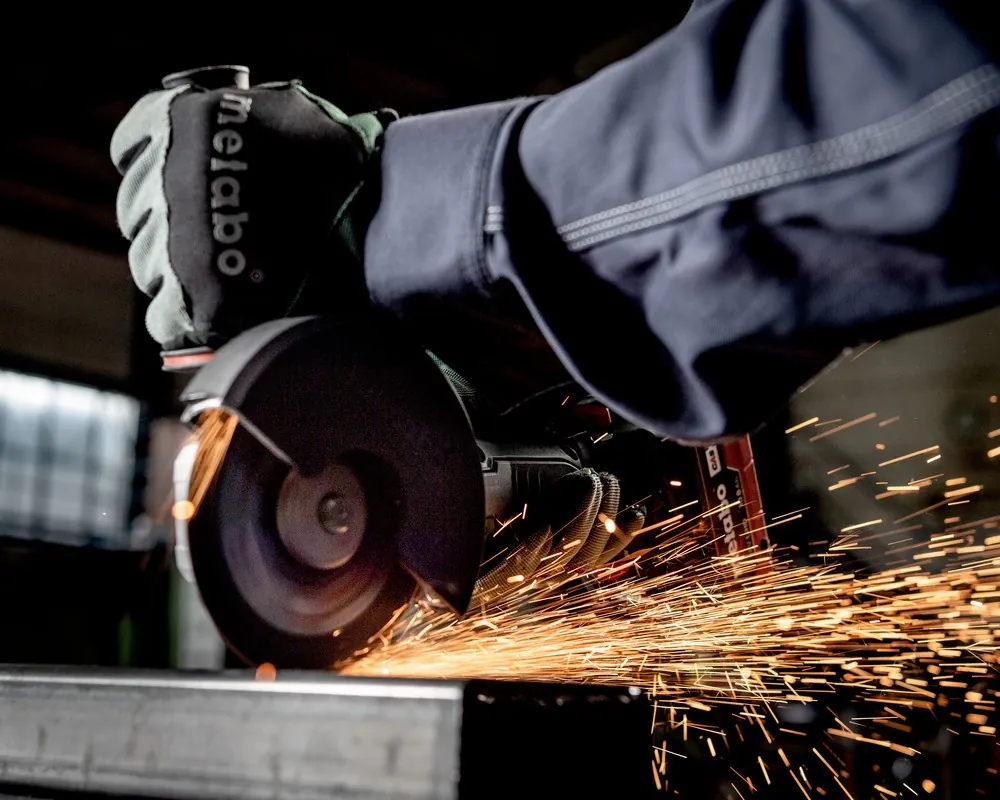 Industrial angle grinder cutting steel with sparks in workshop environment